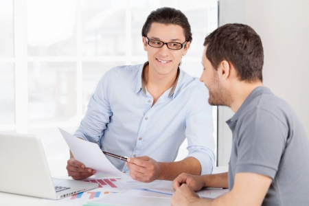 Discussing a new project. Two cheerful business people in casual wear discussing something while one of them pointing document and smilingの写真素材