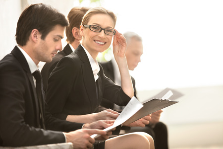 Confident businesswoman. Four people in formalwear waiting in line while beautiful woman looking at camera and smilingの写真素材