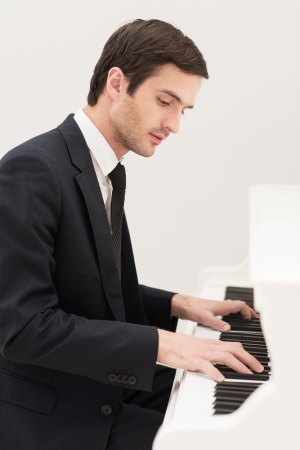 Music is everything. Confident young man in formalwear playing pianoの写真素材