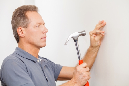 Man hammering a nail. Confident mature grey hair man hammering a nail の写真素材