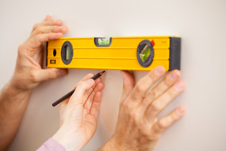 Helping hand. Close-up of two people taking wall measurements の写真素材