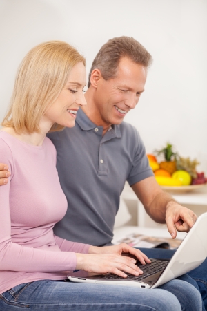 Surfing web together. Side view cheerful mature couple using laptop together and smilingの写真素材