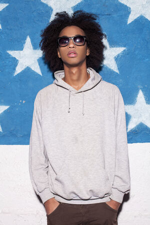 Cool and casual. Young African man in sunglasses standing against American flagの写真素材