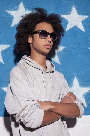Cool and confident. Young African man in sunglasses standing and keeping arms crossedの写真素材