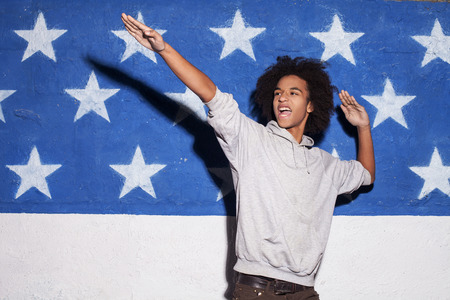 Young and carefree. Young African man posing against American flag and gesturingの写真素材