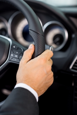 Driving a car. Close-up of male hand on car wheelの写真素材