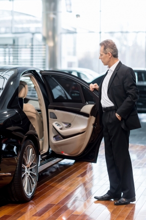 Examining car at dealership. Full length of confident mature man in formalwear opening the car door at the dealershipの写真素材