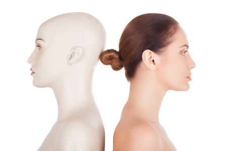Side view of beautiful young shirtless woman standing her back to the mannequin and looking away while isolated on white backgroundの写真素材