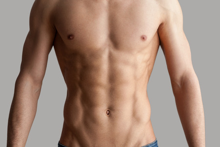 Having a perfect form. Cropped image of muscular man standing isolated on grey backgroundの写真素材