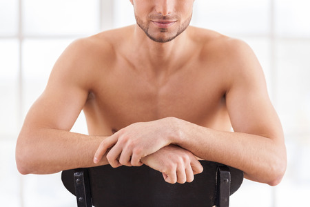 Strong and confident. Cropped image of handsome young muscular man sitting on the chair の写真素材