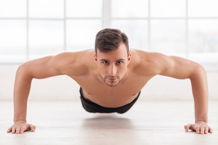 Push-ups. Young muscular man doing push-ups and looking at cameraの写真素材