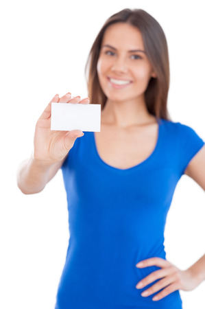 Copy space on her hand. Attractive young smiling woman showing a business card and smiling while standing isolated on whiteの写真素材