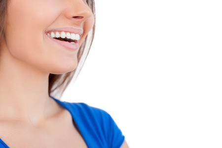 Happy smile. Cropped image of beautiful young woman smiling and looking away while isolated on whiteの写真素材