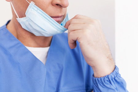 mature doctor taking off his surgical mask の写真素材