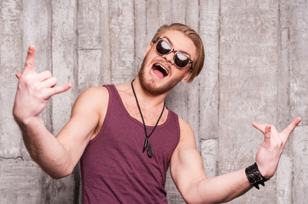 Cool and funky. Handsome young man in sunglasses making a face and gesturing の写真素材
