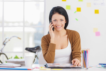 On the phone. Cheerful young businesswoman in casual wear talking on the phone and の写真素材
