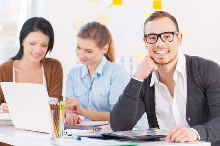 Smiling businessman. Portrait of thoughtful young man with executives working in backgroundの写真素材