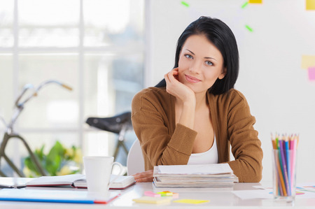 Casual business woman. Portrait of a beautiful young business woman sitting at her working place.の写真素材