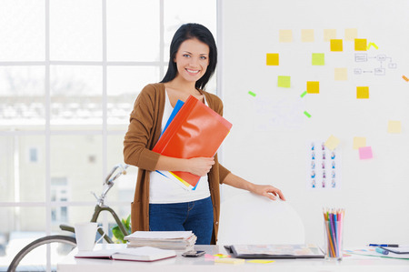 Female assistant. Smiling business woman holding reports and looking at cameraの写真素材