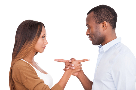 Blaming each other. Beautiful young African couple pointing each other while standing isolated on white backgroundの写真素材