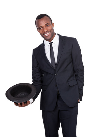 Confident and charming. Handsome young African man in full suit holding a hat in his hand and smiling while standing isolated on white background の写真素材