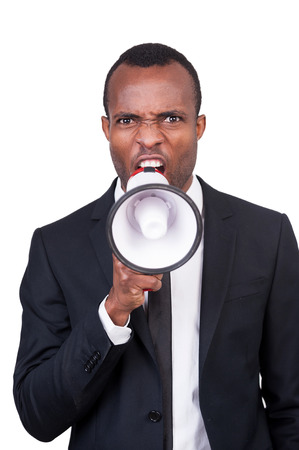 Furious boss. Angry young African man in formalwear shouting at megaphone while standing isolated on white background の写真素材