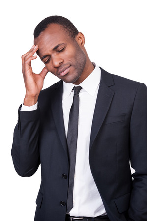 Tired businessman. Young African man in formalwear touching his head with hand and keeping eyes closed while standing isolated on white background の写真素材