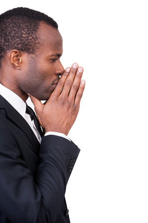 Thinking about new solutions. Side view of thoughtful young African man in formalwear touching his chin with clasped hands while standing isolated on white background の写真素材