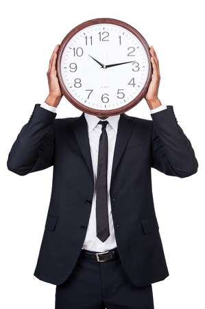 Time management. Man in formalwear holding clock over his face while standing isolated on white backgroundの写真素材