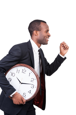 Confidence and punctuality. Side view of cheerful young African man in formalwear running with clock in his hand and isolated on white background の写真素材