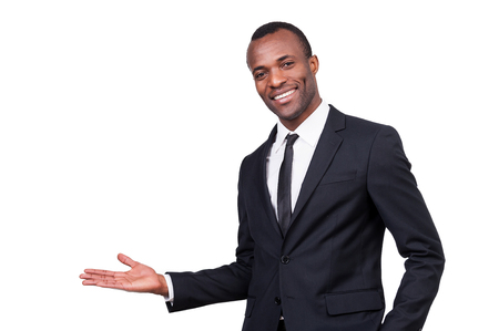 Welcome! Handsome young African man in formalwear gesturing and smiling while standing isolated on white background の写真素材