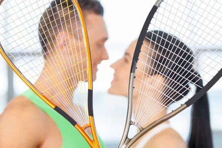 Loving couple kissing behind tennis racketの写真素材