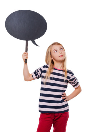 Thinking about... Thoughtful little girl holding a copy space and looking away while standing isolated on whiteの写真素材