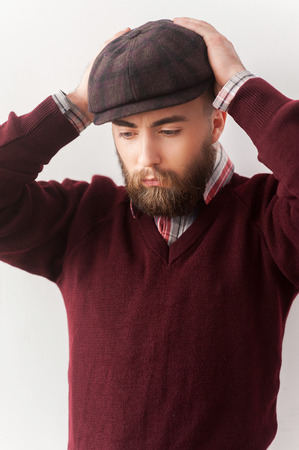 Stylish handsome. Handsome young man in casual wear touching his hat with hand and looking away の写真素材