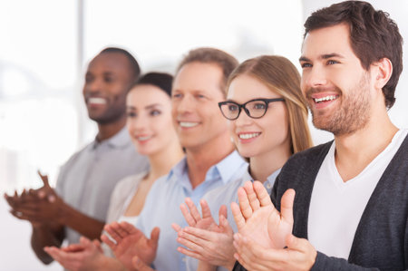 Applauding to corporate innovations. Group of cheerful business people applauding to someone  while...