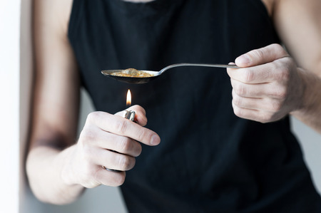 Boiling heroin. Close-up of man boiling heroin in spoonの写真素材