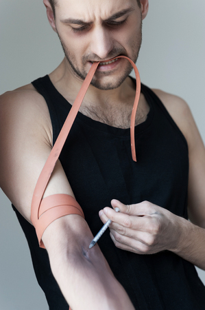  Young man making a heroin injection in armの写真素材