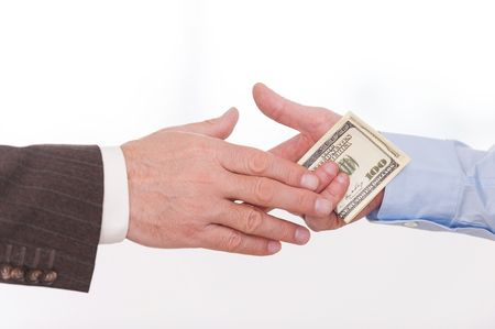 Corruption. Close-up of businessman giving money to another man while handshaking の写真素材