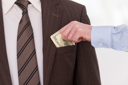Bribing. Close-up of businessman putting money to the pocket of another man in formalwearの写真素材