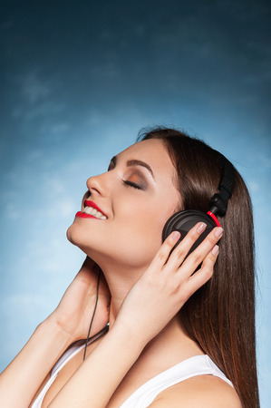 Listening to her favorite music. Beautiful young woman in headphones listening to the music with eyes closedの写真素材