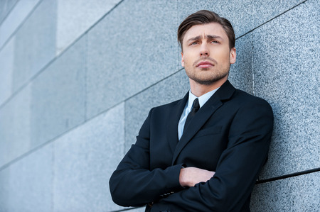 Thinking about business solutions. Thoughtful young man in formalwear keeping arms crossed and looking awayの写真素材