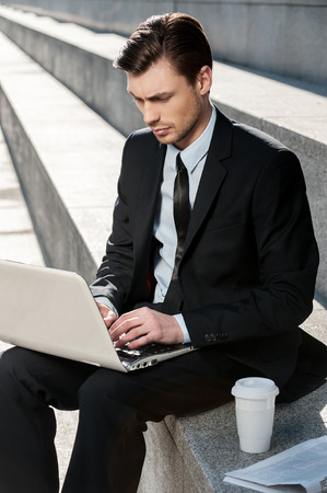 Working Outdoors. Cropped image of Cheerful businessman using laptop の写真素材