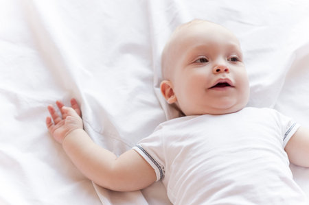 Cute little baby. Top view of cute little baby lying in bed