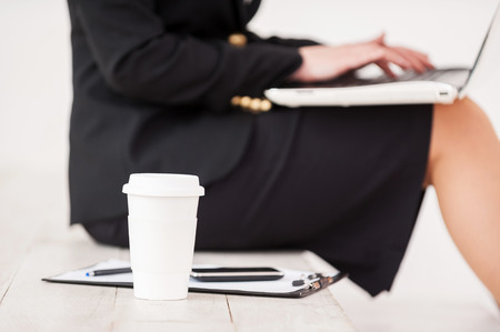 Businesswoman at work. Cropped side view image of businesswoman sitting at the staircase and working on laptopの写真素材