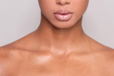 Beautiful lips. Cropped image of beautiful young Afro-American shirtless woman standing while isolated on gray backgroundの写真素材