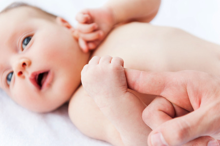 Parents support. Close-up of little baby holding fathers fingerの写真素材