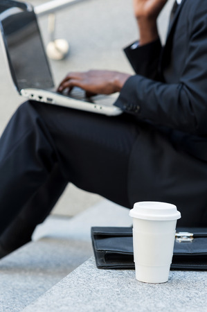 Working outdoors. Cropped image of businessman working on laptop while sitting at staircase outdoorsの写真素材