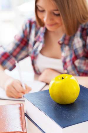 Confident schoolgirl. Top view of cheerful teenage girl studying while sitting at the deskの写真素材
