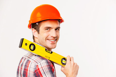 Cheerful construction worker. Rear view of handsome young handyman with carrying work tool on...
