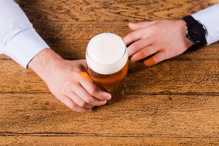 Beer time. Top view of male hands holding beer glass on the bar counter の写真素材